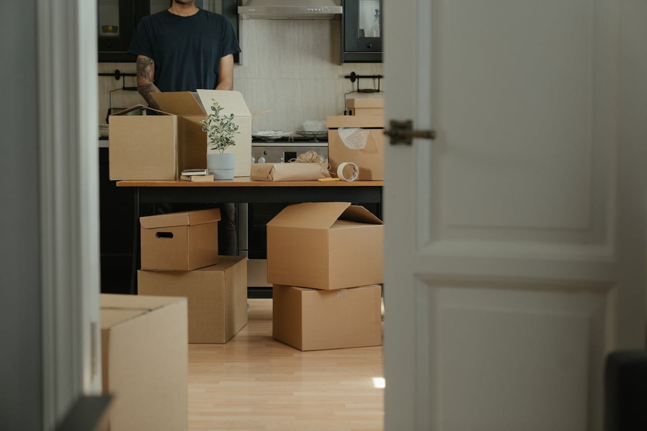 Person unpacking cardboard boxes in a modern kitchen during relocation.